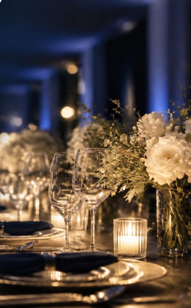 Detalhe de mesa posta com velas, taças e flores brancas (imagem ilustrativa)